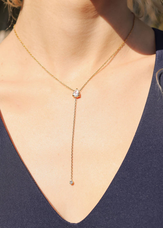 Gold necklace with a pendant on a person wearing a navy blue top.